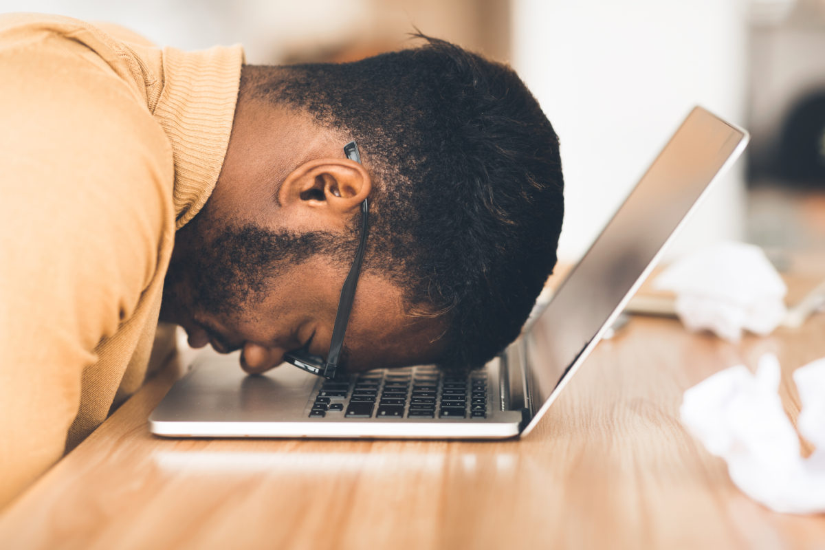 Employee face-down on their laptop, suffering from burnout
