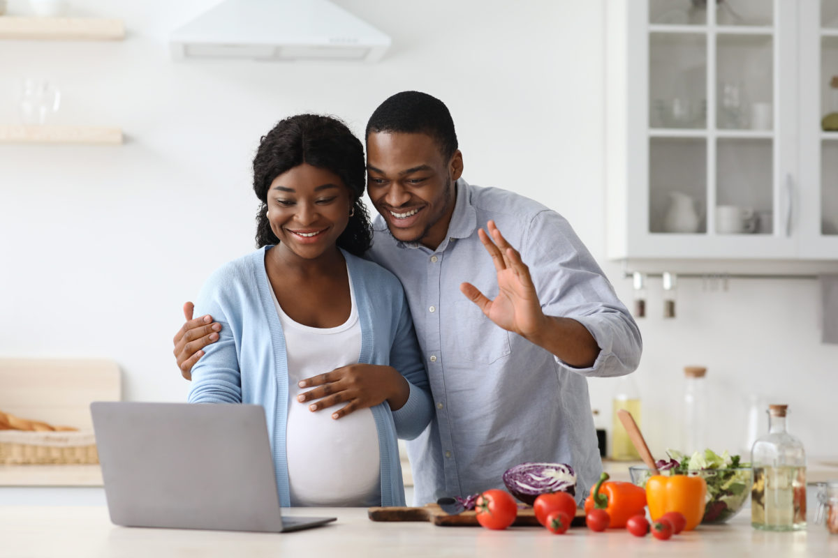 Pregnant Black couple taking part in a virtual baby shower cooking activity