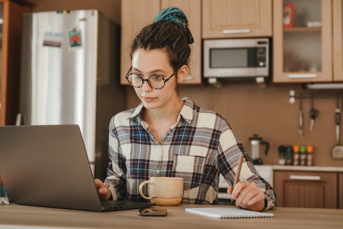 Woman in kitchen looking at computer.